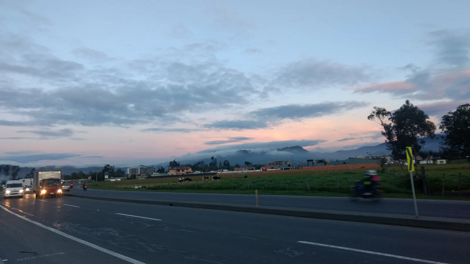 Carretera de doble calzada al atardecer con vehículos circulando con las luces encendidas