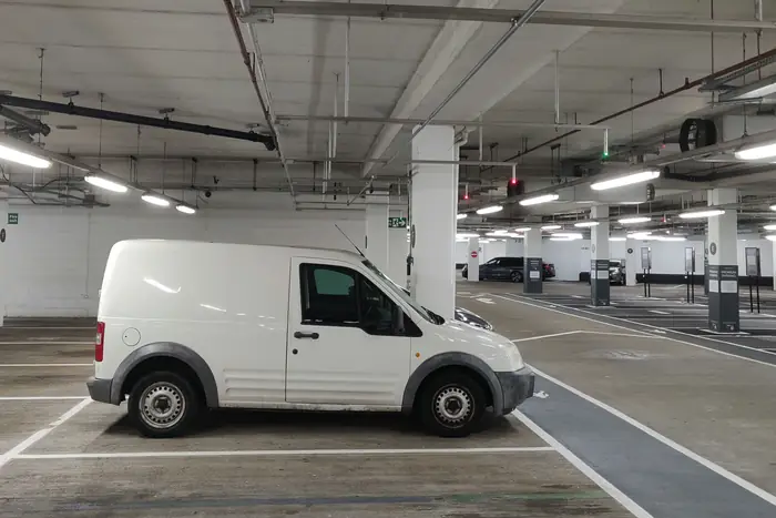 Parqueadero cubierto con señalización de cupos y una camioneta estacionada