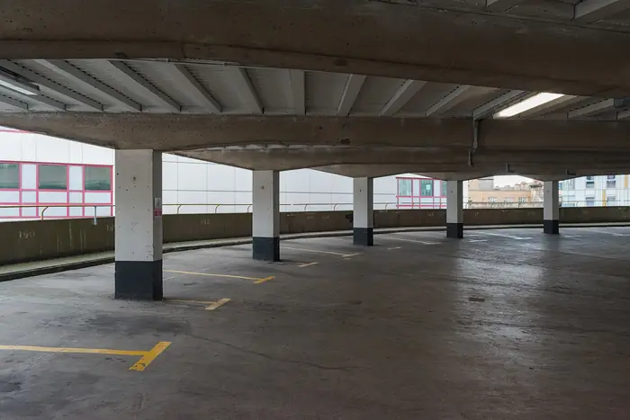Parqueadero cubierto con columnas y demarcación amarilla en el piso