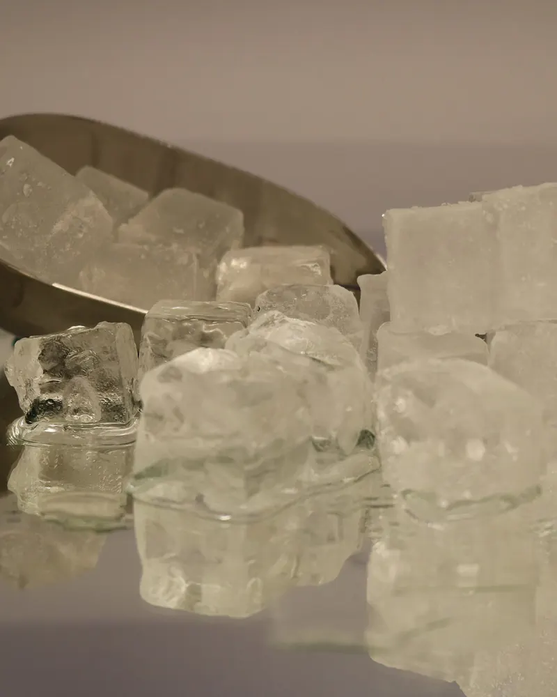 Pala de acero inoxidable con cubos de hielo transparentes sobre una superficie limpia