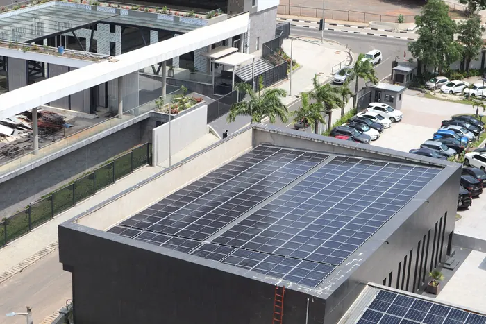 Cubierta plana de un edificio comercial con paneles solares y un estacionamiento al lado