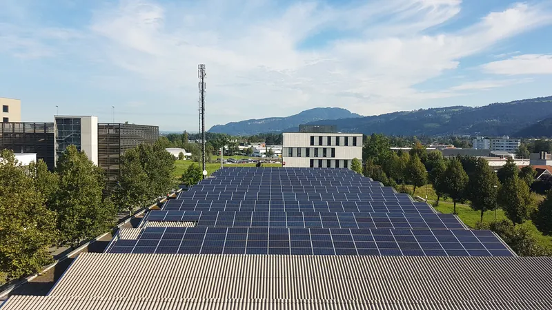Cubierta de una nave industrial cubierta por filas de paneles solares, con montañas al fondo