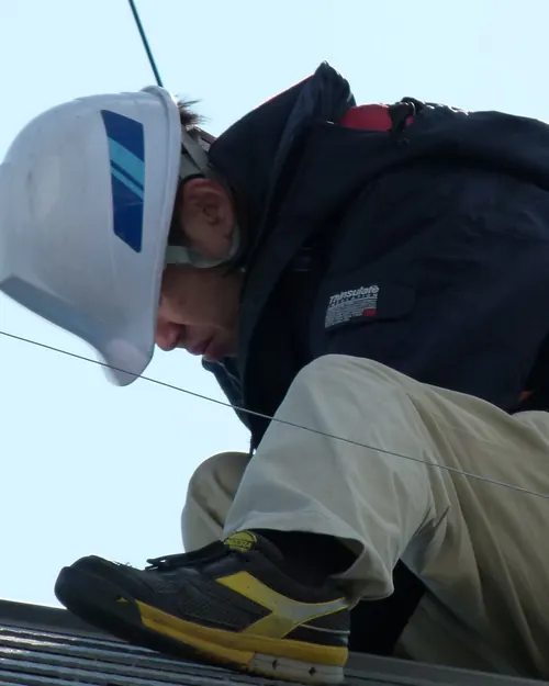 Técnico con casco blanco trabajando sobre la estructura de una cubierta solar