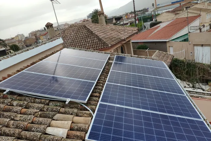 Paneles solares instalados sobre un tejado de teja de barro en una zona residencial